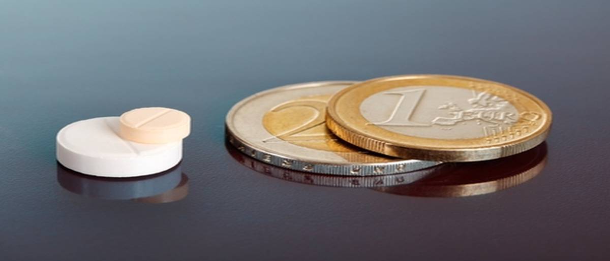 Closeup on pair of stacked pills near pair of similarly arranged euro coins
